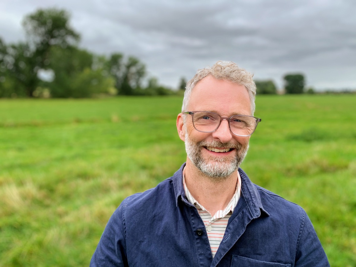 man with glasses smiling in a field